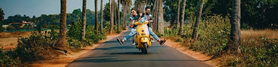 man and woman riding scooter in tropical setting