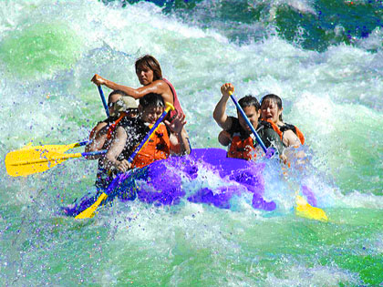 a purple raft full of people in a rushing aqua colored river